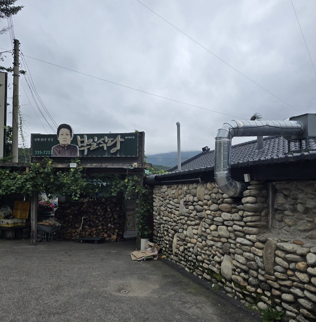 강원도 진부맛집 부일식당 외관, 돌담과 장작이 쌓인 식당 입구